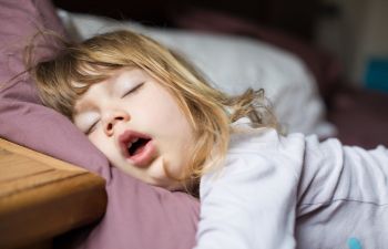 A little girl sleeping with her mouth open.