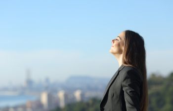 A businesswoman breathing fresh air through her nose.